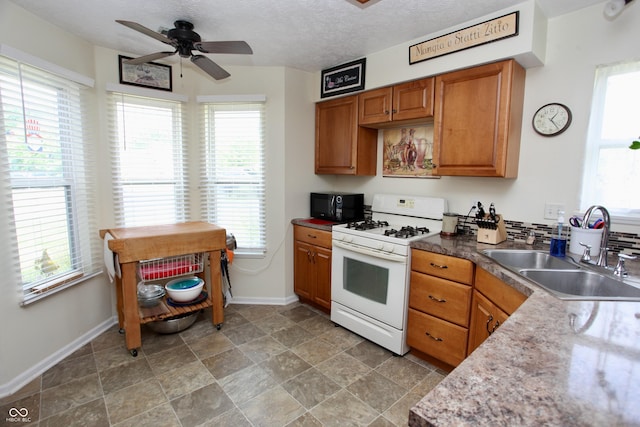 2909 Inverrary Ct, Indianapolis, IN 46234 - kitchen with white gas range oven, black microwave, a ceiling fan, brown cabinetry, and stone finish floors