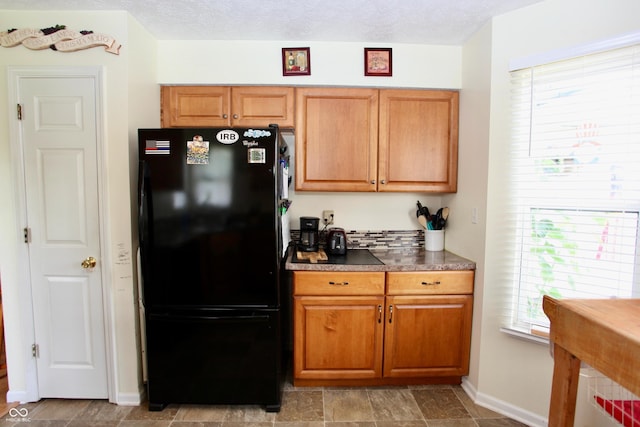 2909 Inverrary Ct, Indianapolis, IN 46234 - kitchen with freestanding refrigerator, brown cabinetry, and dark countertops