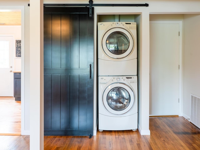 945 E Worthsville Rd, Greenwood, IN 46143 - washroom featuring stacked washing machine and dryer, wood finished floors, and a barn door