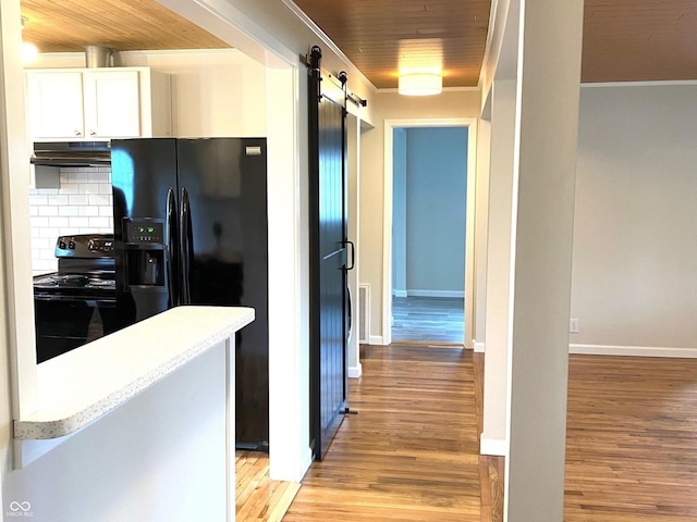 945 E Worthsville Rd, Greenwood, IN 46143 - kitchen with black appliances, under cabinet range hood, a barn door, light wood-style flooring, and ornamental molding