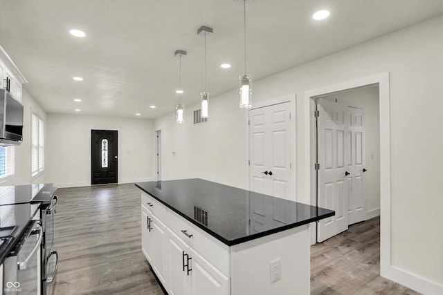 1923 N Parker Ave, Indianapolis, IN 46218 - kitchen with dark countertops, light wood-style flooring, stainless steel microwave, recessed lighting, and a kitchen island