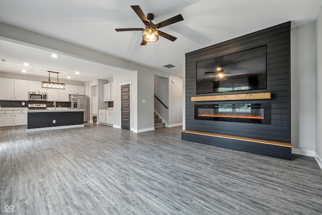 7225 Lockford S, Avon, IN 46123 - unfurnished living room with a large fireplace, wood finished floors, stairs, recessed lighting, and a ceiling fan