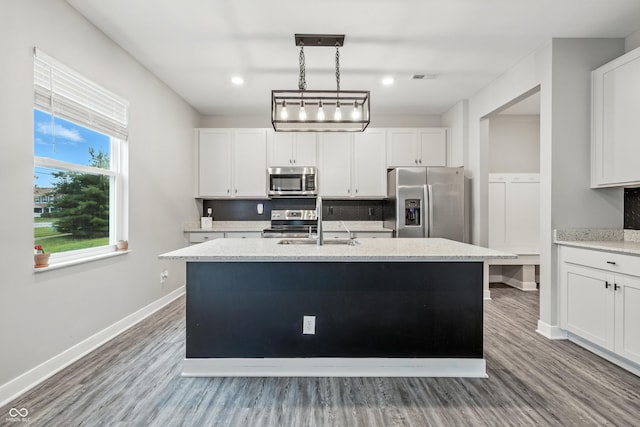 7225 Lockford S, Avon, IN 46123 - kitchen featuring appliances with stainless steel finishes, a center island with sink, wood finished floors, white cabinets, and pendant lighting