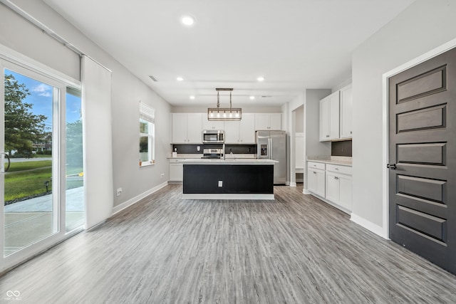 7225 Lockford S, Avon, IN 46123 - kitchen with appliances with stainless steel finishes, light countertops, light wood-style flooring, white cabinetry, and a kitchen island with sink