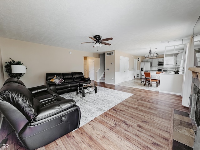 1381 Harrison Dr, Greenwood, IN 46143 - living room with light wood-type flooring, stairway, ceiling fan, and a fireplace with flush hearth