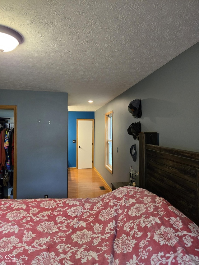 310 Tiffany Ln, North Vernon, IN 47265 - bedroom with a textured ceiling, a walk in closet, wood finished floors, a closet, and recessed lighting