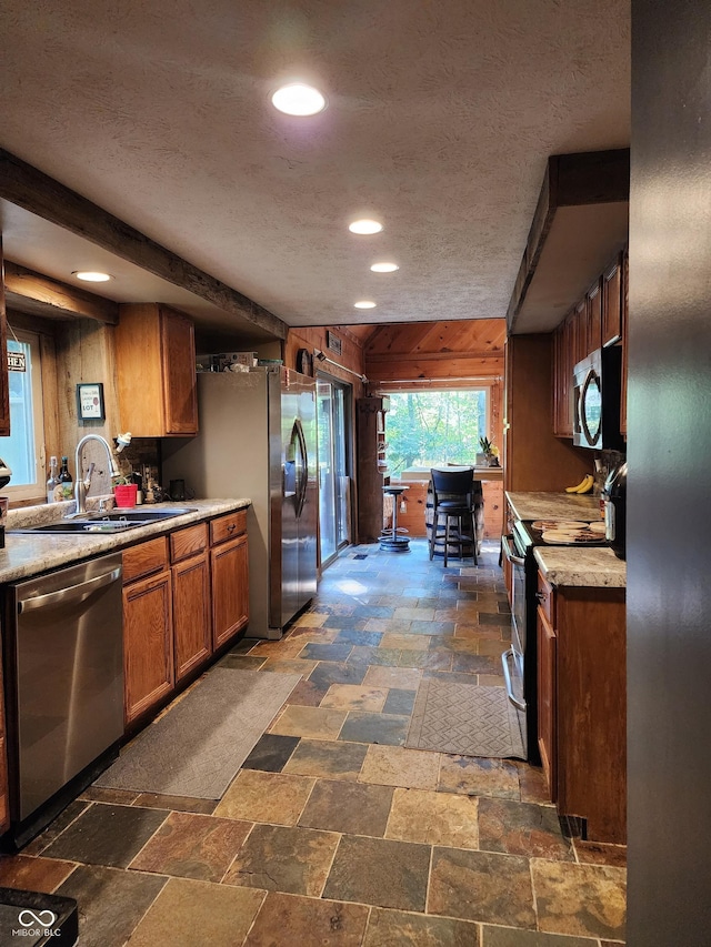 6774 S Becks Grove Rd, Freetown, IN 47235 - kitchen with stainless steel appliances, stone tile flooring, brown cabinets, a textured ceiling, and light countertops
