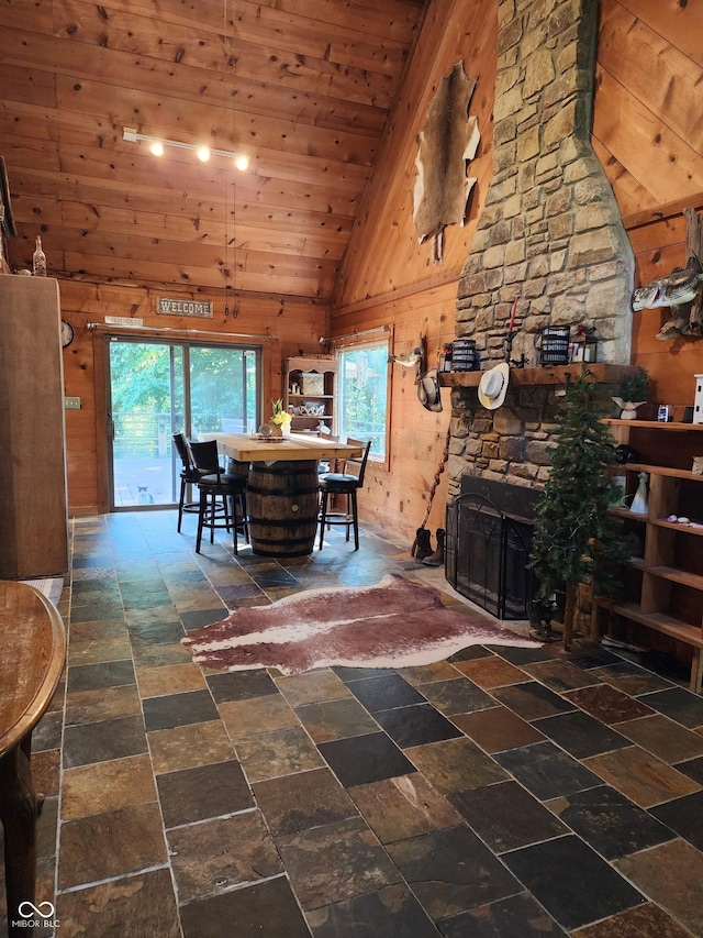 6774 S Becks Grove Rd, Freetown, IN 47235 - dining space featuring lofted ceiling, wood walls, wood ceiling, stone finish flooring, and a stone fireplace