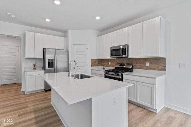 7265 Governors Row, Avon, IN 46123 - kitchen featuring appliances with stainless steel finishes, light wood-style flooring, an island with sink, tasteful backsplash, and white cabinets