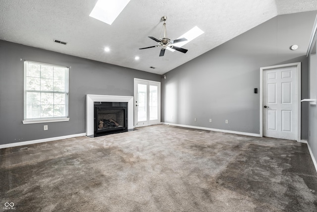 12956 Shandon Ln, Fishers, IN 46038 - unfurnished living room featuring vaulted ceiling, a skylight, a textured ceiling, ceiling fan, and a fireplace with flush hearth