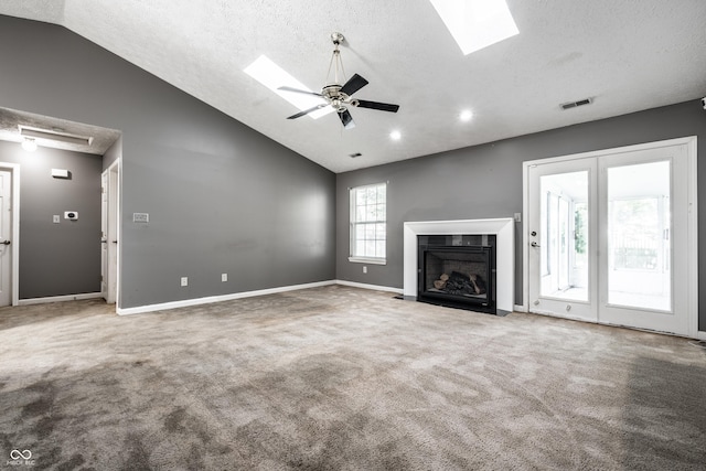 12956 Shandon Ln, Fishers, IN 46038 - unfurnished living room featuring vaulted ceiling, carpet flooring, a skylight, a textured ceiling, and a fireplace with flush hearth