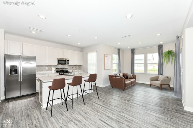 2234 S Bingham Pl, New Palestine, IN 46163 - kitchen featuring appliances with stainless steel finishes, light wood-style flooring, a center island with sink, backsplash, and recessed lighting