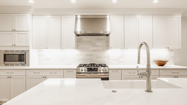 35 E 58th St, Indianapolis, IN 46220 - kitchen featuring wall chimney exhaust hood, stainless steel appliances, white cabinetry, tasteful backsplash, and recessed lighting