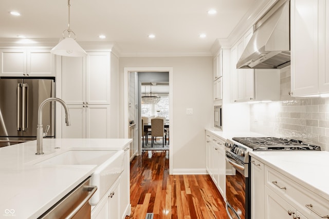 35 E 58th St, Indianapolis, IN 46220 - kitchen with appliances with stainless steel finishes, wall chimney exhaust hood, light countertops, white cabinets, and wood finished floors