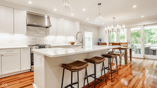 35 E 58th St, Indianapolis, IN 46220 - kitchen with wall chimney range hood, stainless steel gas stove, light wood finished floors, ornamental molding, and decorative backsplash