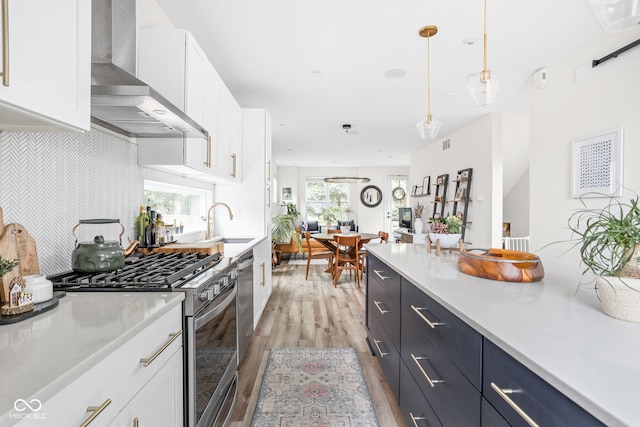 2539 Broadway St, Indianapolis, IN 46205 - kitchen with wall chimney exhaust hood, stainless steel appliances, light wood-style floors, white cabinets, and light countertops