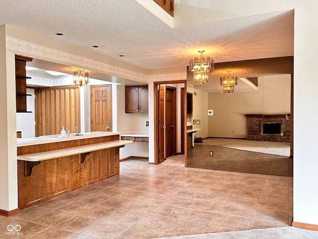 5720 Bayside Dr, Fort Wayne, IN 46815 - bathroom with a chandelier, a textured ceiling, tile patterned flooring, a brick fireplace, and vanity