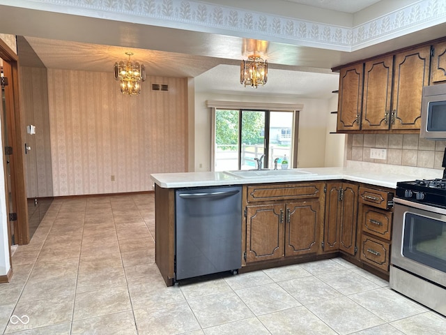5720 Bayside Dr, Fort Wayne, IN 46815 - kitchen featuring appliances with stainless steel finishes, a peninsula, a chandelier, light countertops, and backsplash