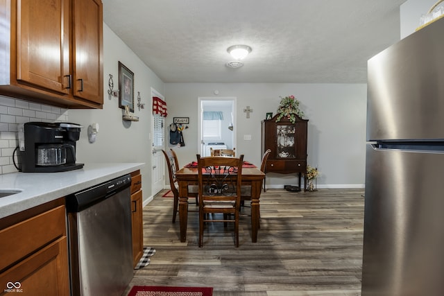 1530 E 26th St, Muncie, IN 47302 - kitchen featuring stainless steel appliances, decorative backsplash, brown cabinetry, dark wood-style floors, and a textured ceiling
