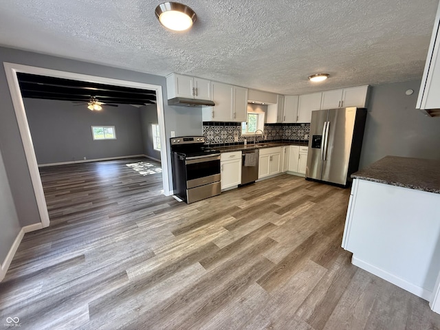 4833 Pennsylvania St, Clayton, IN 46118 - kitchen with appliances with stainless steel finishes, dark countertops, under cabinet range hood, wood finished floors, and decorative backsplash