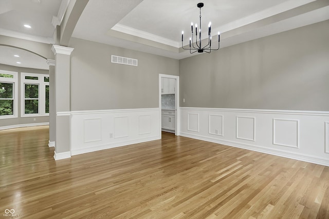 7131 Nile Ridge Ct, Indianapolis, IN 46236 - unfurnished dining area featuring light wood-style flooring, arched walkways, a wainscoted wall, ornate columns, and a chandelier