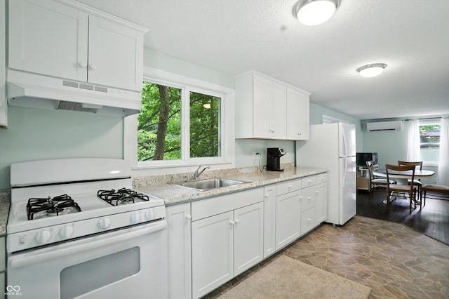 8453 S Christian Dr, Princes Lakes, IN 46164 - kitchen with white appliances, under cabinet range hood, a wall unit AC, white cabinetry, and stone finish floors