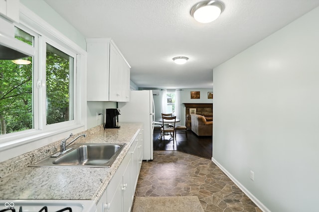 8453 S Christian Dr, Princes Lakes, IN 46164 - kitchen featuring light countertops, dark stone finish flooring, white cabinetry, freestanding refrigerator, and a textured ceiling