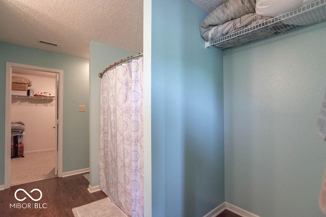 8703 Mellot Way, Camby, IN 46113 - full bathroom featuring wood finished floors, a textured ceiling, a spacious closet, and a shower with curtain