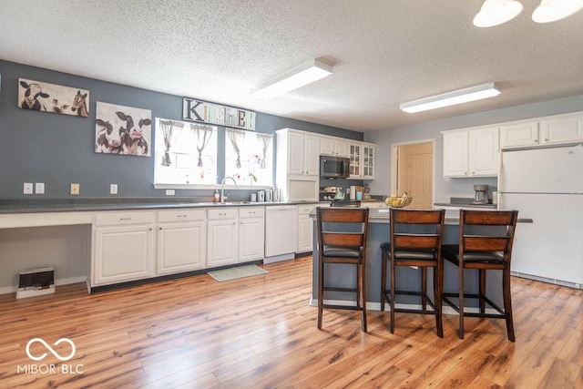 8703 Mellot Way, Camby, IN 46113 - kitchen featuring white appliances, white cabinetry, a textured ceiling, light wood-style floors, and a breakfast bar area