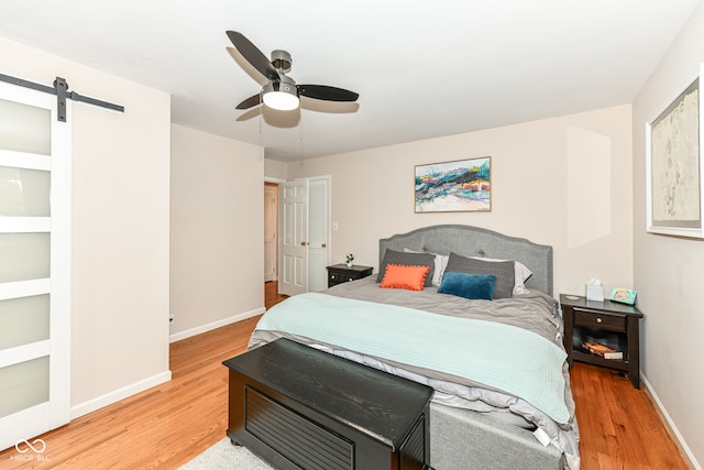 7014 Creekside Ln, Indianapolis, IN 46220 - bedroom featuring light wood-type flooring, a barn door, and a ceiling fan