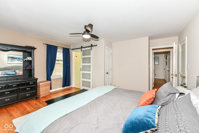 7014 Creekside Ln, Indianapolis, IN 46220 - bedroom with light wood-type flooring, a barn door, and ceiling fan