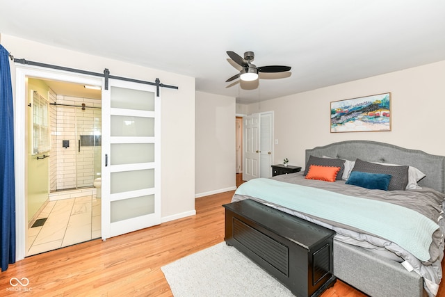 7014 Creekside Ln, Indianapolis, IN 46220 - bedroom featuring a barn door, light wood-style flooring, connected bathroom, and ceiling fan