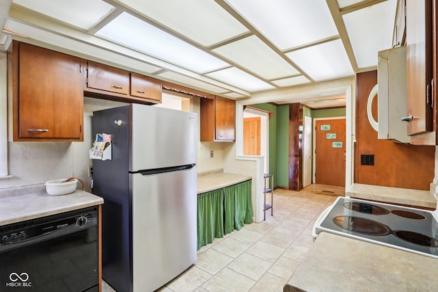 202 W Elbert St, Indianapolis, IN 46217 - kitchen with freestanding refrigerator, black dishwasher, stove, light countertops, and light tile patterned floors