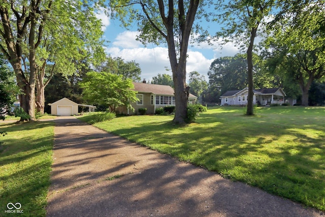 202 W Elbert St, Indianapolis, IN 46217 - view of front facade featuring a garage, driveway, an outbuilding, a front lawn, and a chimney