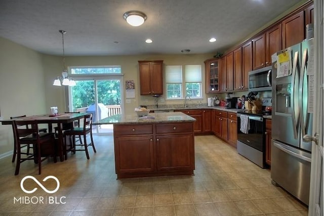11275 Catalina Dr, Fishers, IN 46038 - kitchen featuring appliances with stainless steel finishes, recessed lighting, a center island, light stone counters, and glass insert cabinets