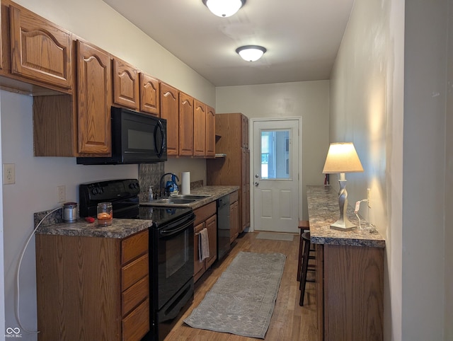 3236 Spruce St, Columbus, IN 47203 - kitchen featuring black appliances, light wood-style flooring, brown cabinets, and dark countertops
