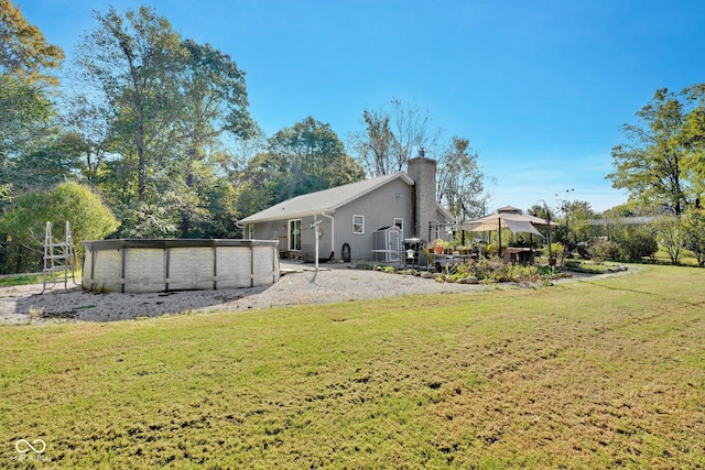 9970 N Brown Ln, Gosport, IN 47433 - rear view of house with a chimney, a covered pool, and a lawn