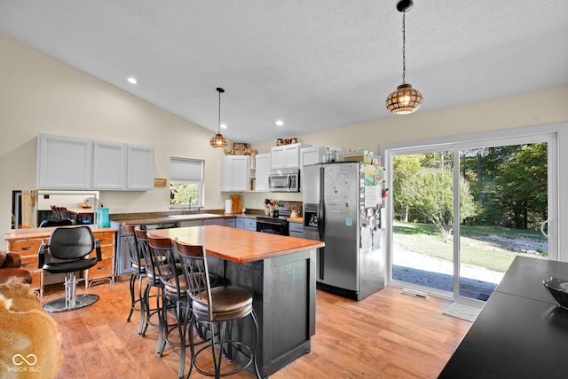 9970 N Brown Ln, Gosport, IN 47433 - kitchen featuring appliances with stainless steel finishes, wood counters, a breakfast bar area, light wood-type flooring, and hanging light fixtures