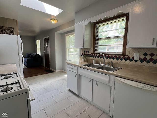 1726 N Linwood Ave, Indianapolis, IN 46218 - kitchen featuring white appliances, a skylight, decorative backsplash, white cabinets, and light tile patterned floors