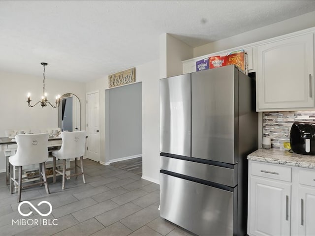 8508 Aviva Ln, Indianapolis, IN 46237 - kitchen featuring freestanding refrigerator, a chandelier, decorative backsplash, white cabinetry, and decorative light fixtures