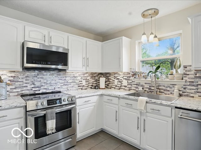 8508 Aviva Ln, Indianapolis, IN 46237 - kitchen featuring appliances with stainless steel finishes, white cabinetry, decorative backsplash, light tile patterned floors, and pendant lighting