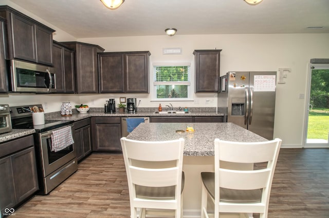 108 Herbert Ct, Trafalgar, IN 46181 - kitchen with stainless steel appliances, dark brown cabinets, light wood-style flooring, a kitchen breakfast bar, and a kitchen island