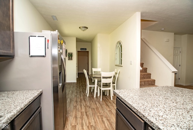 108 Herbert Ct, Trafalgar, IN 46181 - kitchen featuring freestanding refrigerator, light wood-style flooring, light stone counters, and dark brown cabinetry