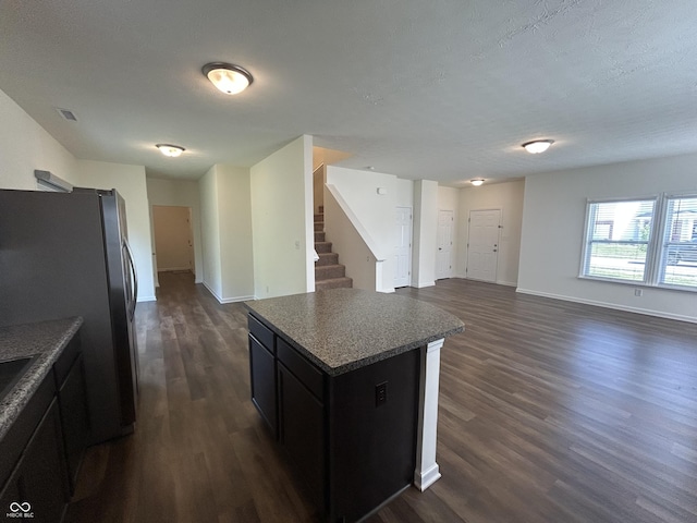 108 Herbert Ct, Trafalgar, IN 46181 - kitchen featuring dark wood-style floors, freestanding refrigerator, open floor plan, a kitchen island, and dark cabinetry