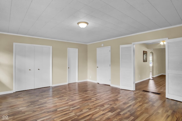 2433 17th St, Columbus, IN 47201 - unfurnished bedroom with wood finished floors, crown molding, and arched walkways