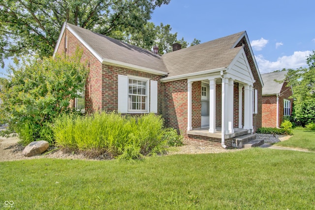 2433 17th St, Columbus, IN 47201 - view of front facade with brick siding, a chimney, a front lawn, and roof with shingles