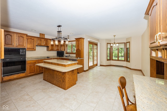 1112 N Dogwood Way, Greenfield, IN 46140 - kitchen with a chandelier, black appliances, brown cabinets, a center island, and decorative light fixtures
