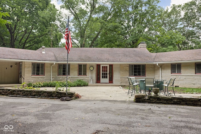 5519 N County Rd 550 E, Pittsboro, IN 46167 - ranch-style house with stone siding, a chimney, a patio area, and roof with shingles