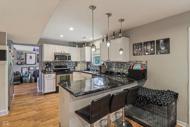 2426 Borgman Ct, Indianapolis, IN 46229 - kitchen featuring appliances with stainless steel finishes, light wood-type flooring, a peninsula, decorative backsplash, and recessed lighting