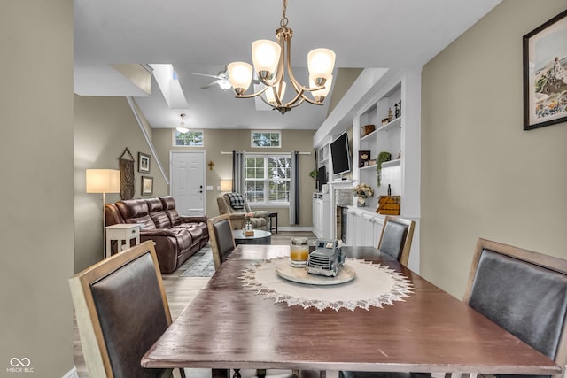 10832 Washington Bay Dr, Fishers, IN 46037 - dining space with a fireplace, a chandelier, a skylight, and light wood-style floors